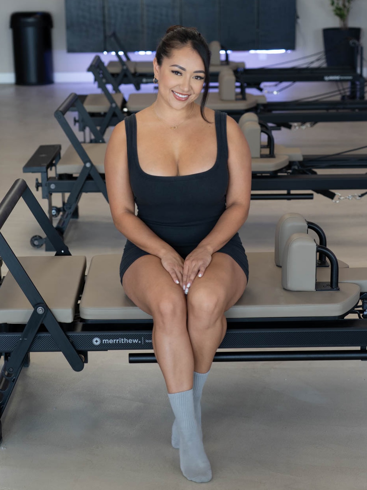 A client seated on a Merrithew reformer inside the Drip Pilates studio.